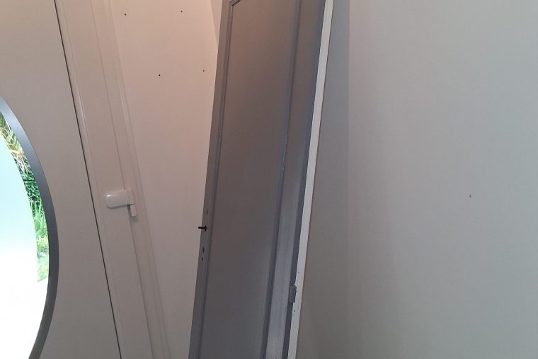 Photographie de la remise en peinture en cours d'une porte moulurée dans un couloir à Chauconin-Neufmontiers